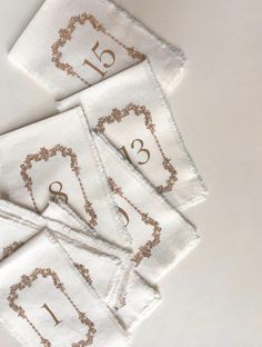 four white napkins with gold numbers on them