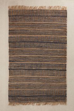 a woven piece of cloth with fringes on top of white fabric and beige background