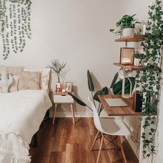 a bed room with a neatly made bed next to a desk and plants on the wall