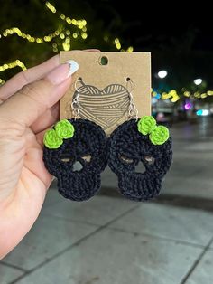 a pair of black crocheted skull earrings with green flowers in the shape of skulls