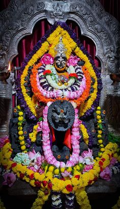 an idol is displayed in front of a red and yellow backdrop with flowers on it