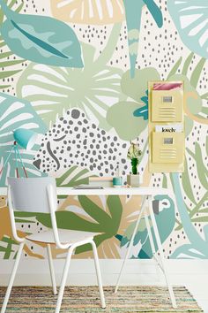 a desk with a chair next to it in front of a colorful wallpaper