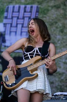 a woman playing a bass guitar on stage