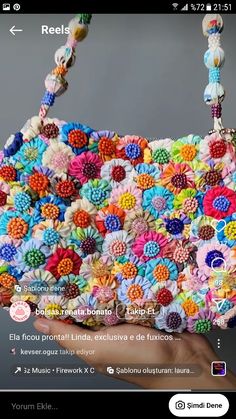 a hand holding a colorful purse made out of beads and flowers on the front of it