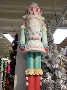 a large colorful statue in the shape of a nutcracker next to a christmas tree