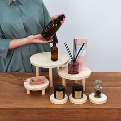 a woman holding a brown bottle over a table with candles and other items on it