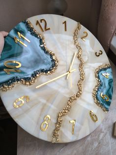 a clock with gold numbers and blue agate stone design on it's face