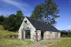 an old stone building sitting on top of a lush green field next to a forest