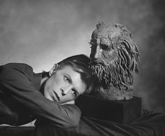 a black and white photo of a woman next to a statue