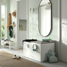 a white room with a mirror, coat rack and other items on the floor in front of it