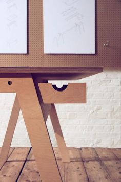 the table is made out of wood and has two pictures hanging on the wall behind it