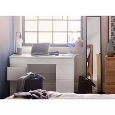 an open laptop computer sitting on top of a white desk next to a mirror and dresser