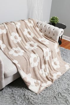 a couch with a blanket on top of it in front of a wall and floor