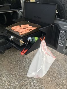 the back of a truck with hot dogs in it and a bag next to it