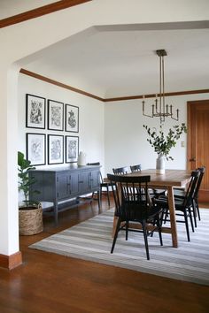 a dining room table with chairs and pictures on the wall