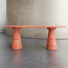 two orange pedestals sitting next to each other on a cement floor in front of a concrete wall