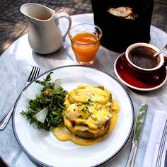 a white plate topped with an omelet next to two cups of tea and silverware