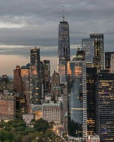 the city skyline is lit up at night, with skyscrapers in the foreground