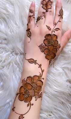 a woman's hand with henna on it and flowers painted on the palm