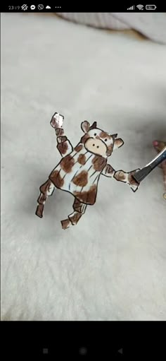 a person holding a pair of scissors in front of a paper cut out of a giraffe