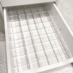 an open drawer on the floor in a room with white tile floors and walls,