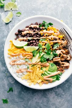 a white plate topped with tacos, rice and guacamole sauce next to a fork