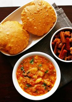 three bowls of food on a table with bread and other foods in the bowl next to them