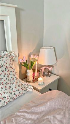 a white bed topped with two nightstands next to a night stand filled with flowers