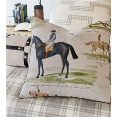 a horse and rider pillow sitting on top of a couch next to two other pillows