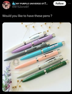 four pens sitting next to each other on top of a white table with flowers in the background