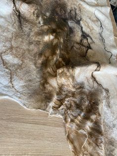 a cat laying on top of a wooden floor next to a table covered in fur