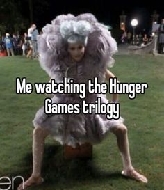 a person sitting on top of a barrel in the grass with words saying me watching the hunger games trilogy