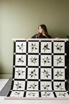 a woman is holding up a quilt made with black and white squares, which are all over the place