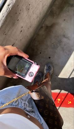 a person holding a cell phone in their hand and sitting on the ground next to a wall