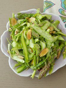 a white bowl filled with green vegetables next to a fork and napkin on top of a table