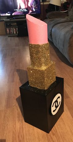 a pink candle sitting on top of a black block in front of a tv set