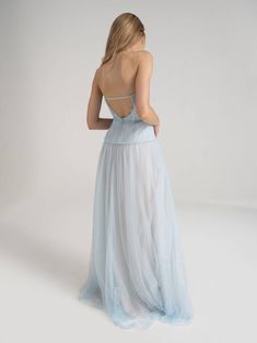 the back of a woman wearing a light blue evening gown with straps and pleaed skirt