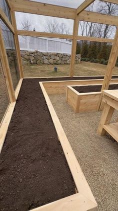 an enclosed area with wooden benches and dirt