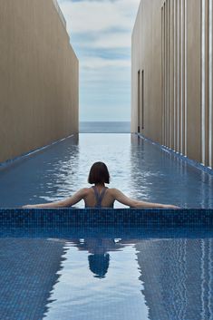 a woman sitting in the middle of a swimming pool with her back to the camera