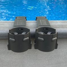 there are two black trash cans next to the pool