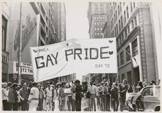 an old black and white photo of people holding a gay pride sign in the street