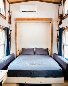 a bed with blue sheets and pillows in a small room