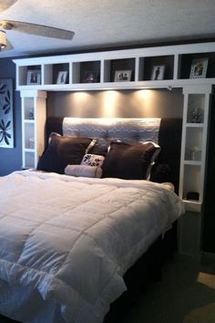 a large bed sitting in the middle of a bedroom next to a wall mounted bookcase