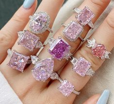 a woman's hand with five different colored diamond rings on top of her fingers