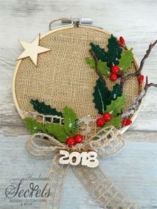 a cross stitch christmas ornament with holly and berries