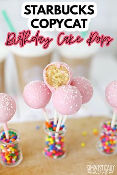 cake pops with sprinkles in glass vases on wooden table next to cupcakes