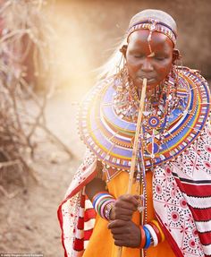 an african woman in traditional clothing holding a stick