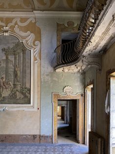 an empty room with paintings on the wall and stairs leading to another room that has no one in it