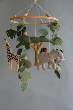 a mobile with an elephant, giraffe and tree on it's sides