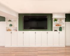 a flat screen tv mounted to the side of a wall in a room with white cabinets